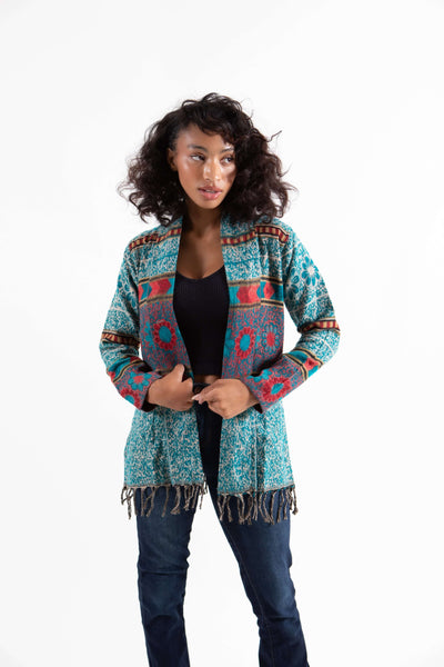 Woman wearing bohemian turquoise fringe cardigan sweater with floral print.